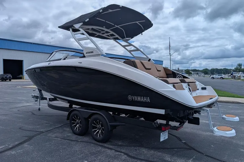 Slide: The Image of 2024 Yamaha Boats 252SE on trailer, sleek design, black and white exterior, parked outdoors. - 10