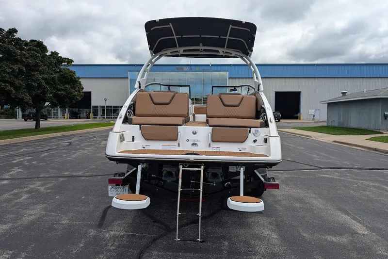 Slide: The Image of 2024 Yamaha Boats 252SE, rear view, parked outdoors with swim platform and ladder. - 11