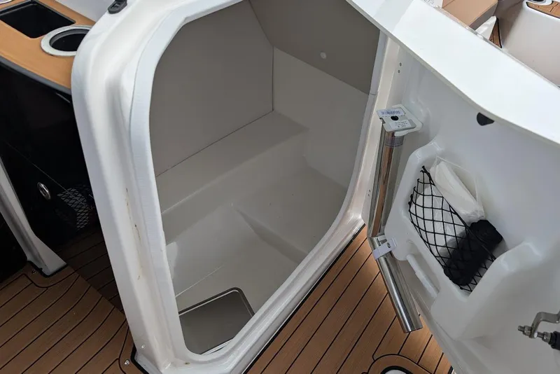 Slide: The Image of 2024 Yamaha Boats 252SE interior storage compartment with wooden flooring and cup holders. - 28