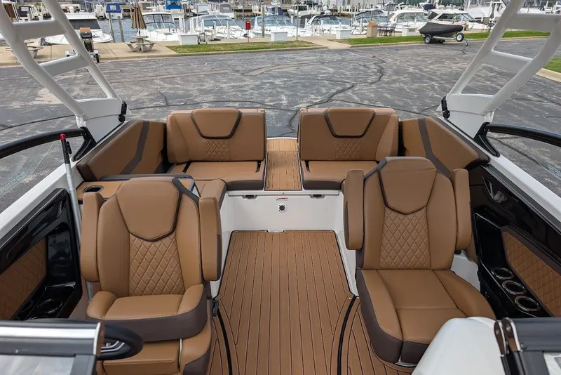 Slide: The Image of 2024 Yamaha Boats 252SE interior with luxurious brown seating and spacious layout at marina. - 38