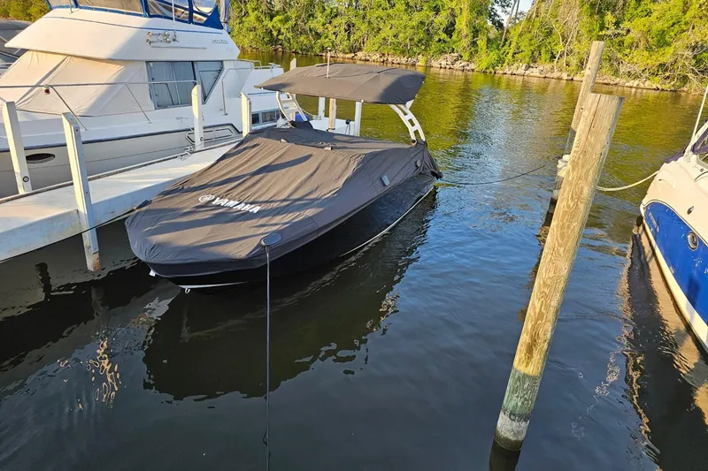 Slide: The Image of 2024 Yamaha Boats 252SE covered at dock, surrounded by water and neighboring boats. - 6