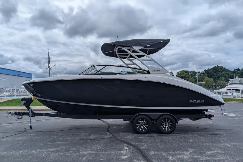 Slide: The Image of 2024 Yamaha Boats 252SE on trailer, sleek black design, parked outdoors under cloudy sky. - 9