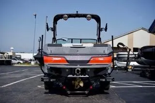 Slide: The Image of 2025 MasterCraft NXT22 boat, rear view, parked outdoors on a sunny day. - 2
