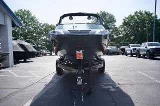 Slide: The Image of 2025 MasterCraft NXT22 boat on trailer in parking lot, surrounded by trees and vehicles. - 6