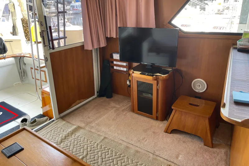 Slide: The Image of 1988 Chris-Craft 392 Sport Fish interior with TV, wooden furniture, and carpeted floor. - 19