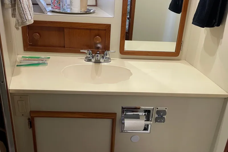 Slide: The Image of 1988 Chris-Craft 392 Sport Fish bathroom with sink, mirror, and wooden cabinetry. - 21