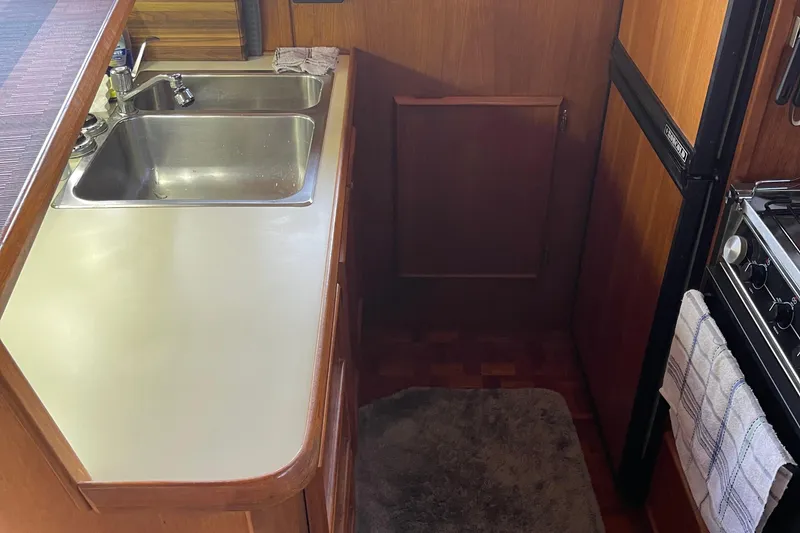 Slide: The Image of 1988 Chris-Craft 392 Sport Fish kitchen with sink, stove, and wooden cabinetry. - 27
