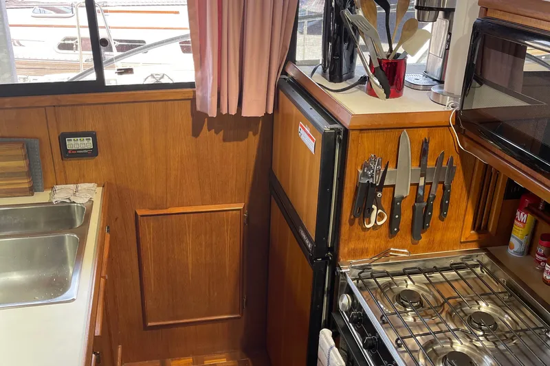 Slide: The Image of 1988 Chris-Craft 392 Sport Fish kitchen with wooden cabinetry, stove, and knife set. - 28
