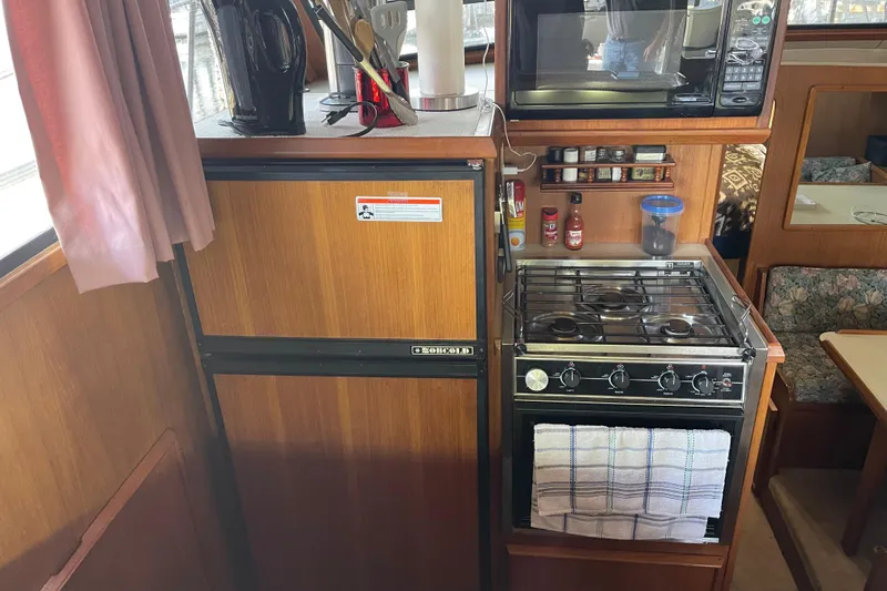 Slide: The Image of 1988 Chris-Craft 392 Sport Fish kitchen with stove, fridge, and microwave. - 29