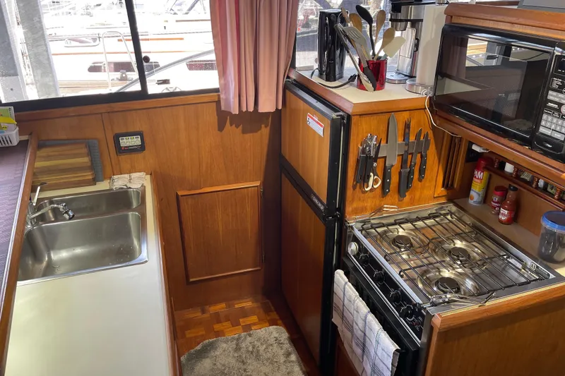 Slide: The Image of 1988 Chris-Craft 392 Sport Fish yacht kitchen with stove, sink, and wooden cabinetry. - 4