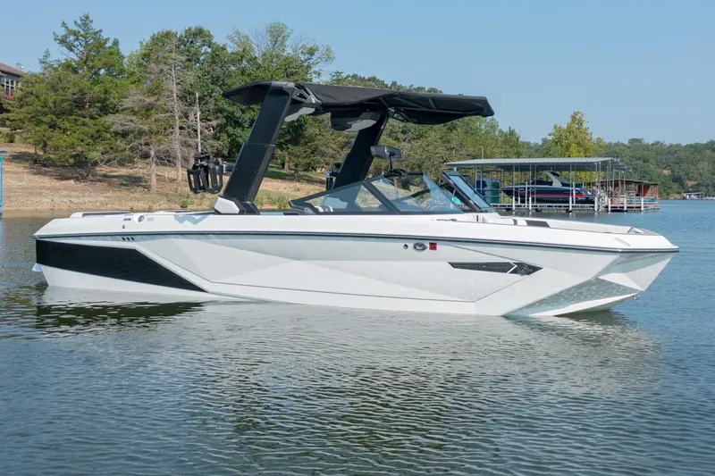 Slide: The Image of 2022 Nautique Super Air Nautique G25 boat on a serene lake with trees in the background. - 4