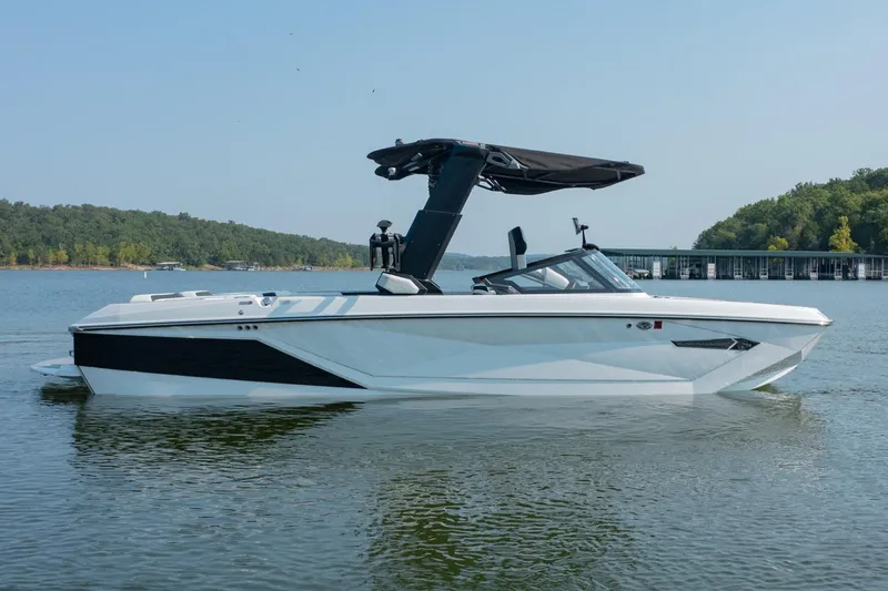 Slide: The Image of 2022 Nautique Super Air Nautique G25 boat on a calm lake with forested shoreline. - 5