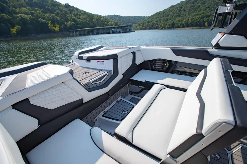 Slide: The Image of 2022 Nautique Super Air Nautique G25 interior with luxurious seating on a scenic lake. - 8