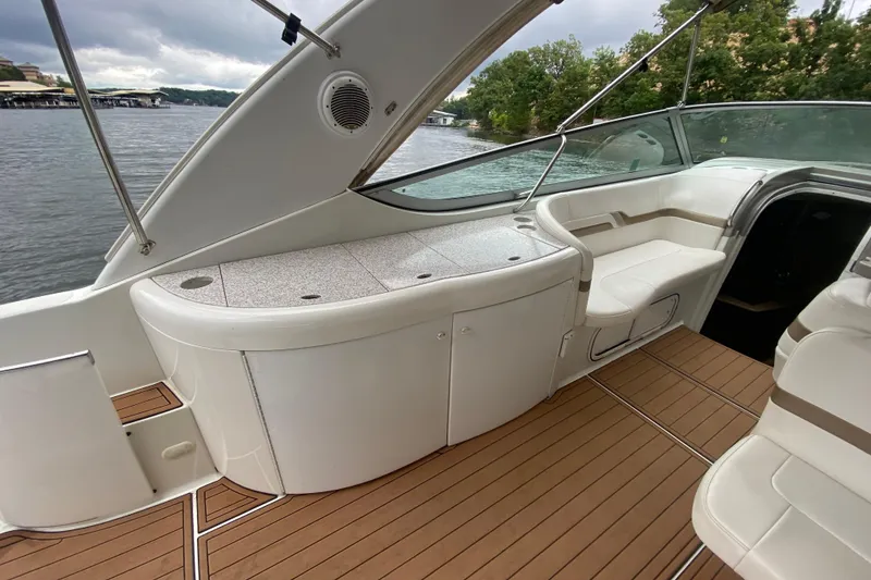 Slide: The Image of 2004 Formula 370ss boat interior with white seating and wooden deck, docked by a lake. - 11
