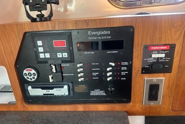 Slide: The Image of Control panel of 2011 Everglades 320 EX boat, featuring 120V AC system and switches. - 11