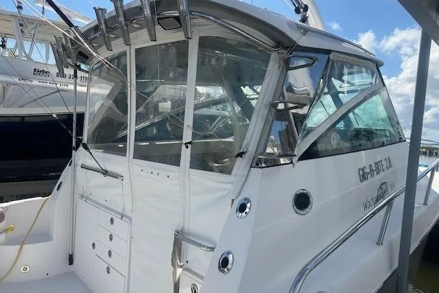 Slide: The Image of 2011 Everglades 320 EX with Tower, docked, featuring sleek design and enclosed cockpit. - 2