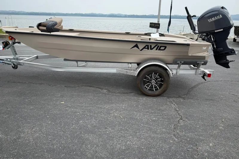The Image of 2026 Avid 16 Commander boat on trailer with Yamaha outboard motor by a lake. - 0