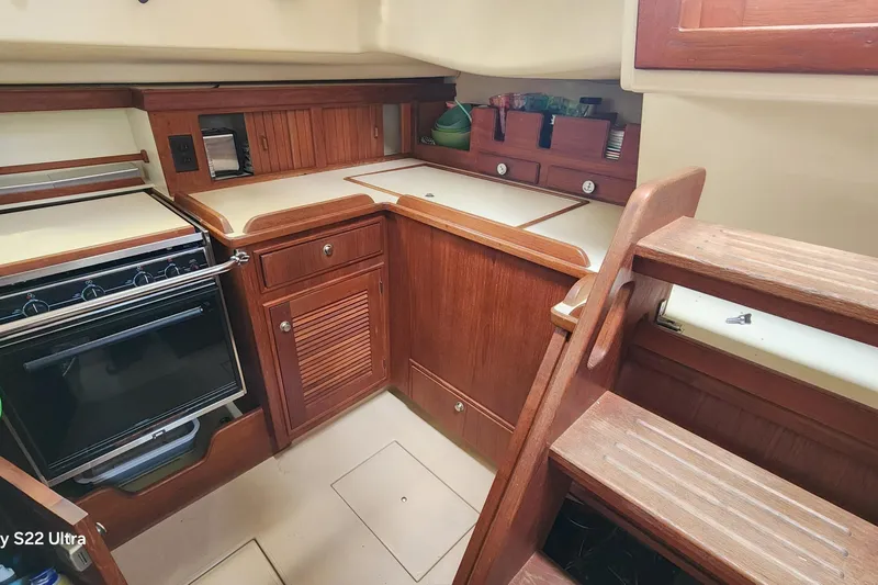 Slide: The Image of Interior of 2000 Island Packet 380 sailboat kitchen with wooden cabinetry and stove. - 22