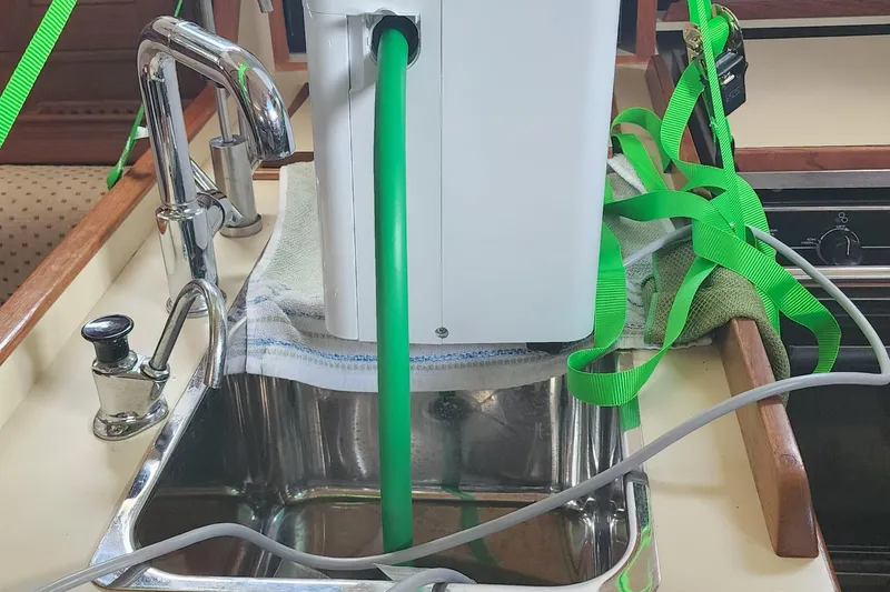 Slide: The Image of Kitchen sink setup on 2000 Island Packet 380 yacht with green hose and faucet. - 25