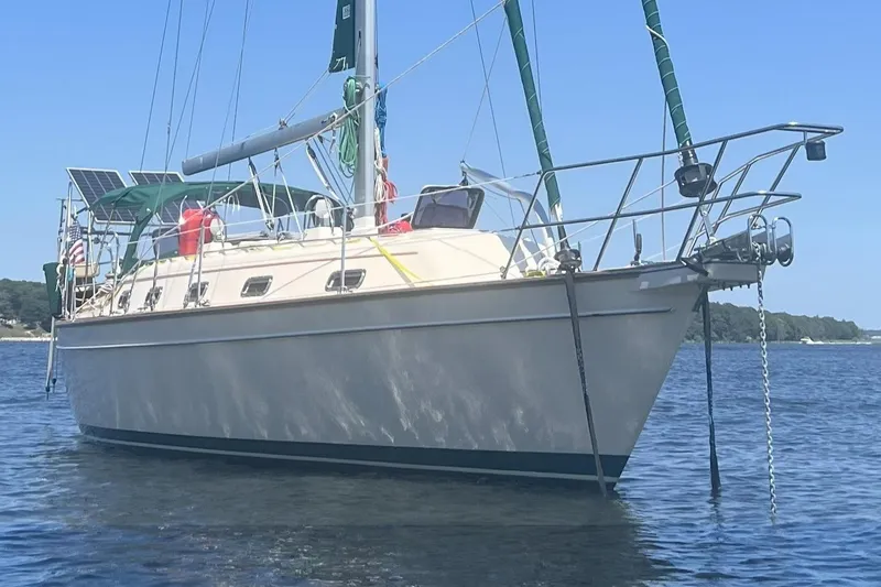 Slide: The Image of 2000 Island Packet 380 sailboat anchored on calm water, featuring solar panels and green sails. - 4