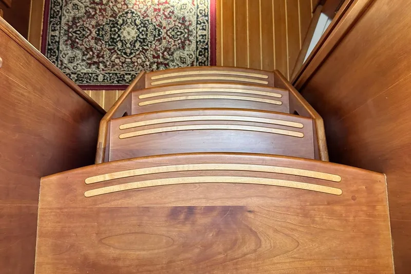 Slide: The Image of Wooden steps inside a 2007 Sabre 386 boat, with a decorative rug visible. - 44