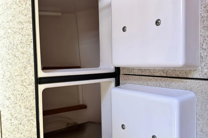 Slide: The Image of Interior storage compartments of a 2007 Sabre 386 boat, featuring white panels and shelving. - 75