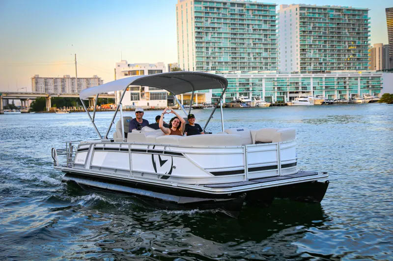 Slide: The Image of 2025 Vision Marine Technologies V24 pontoon boat cruising on urban waterfront. - 10