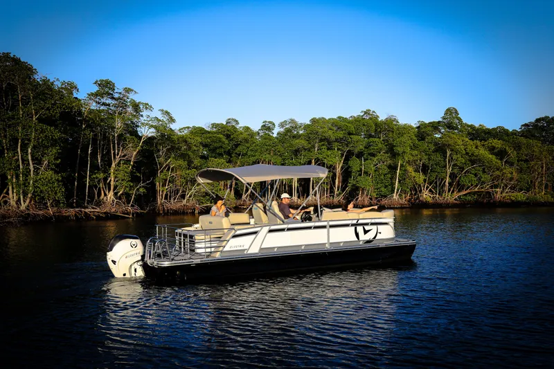 Slide: The Image of 2025 Vision Marine Technologies V24 boat cruising on a serene river with lush greenery. - 2