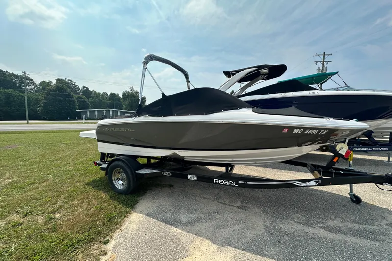 The Image of 2013 Regal 1900 Bowrider boat on trailer, parked on grass under a clear sky. - 0