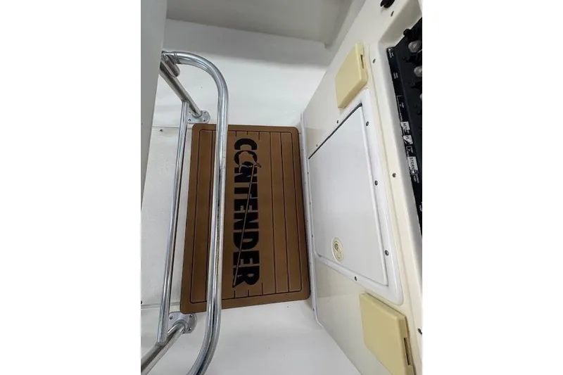 Slide: The Image of 2003 Contender 27 Open boat with dual Yamaha engines on a trailer near a warehouse. - 7