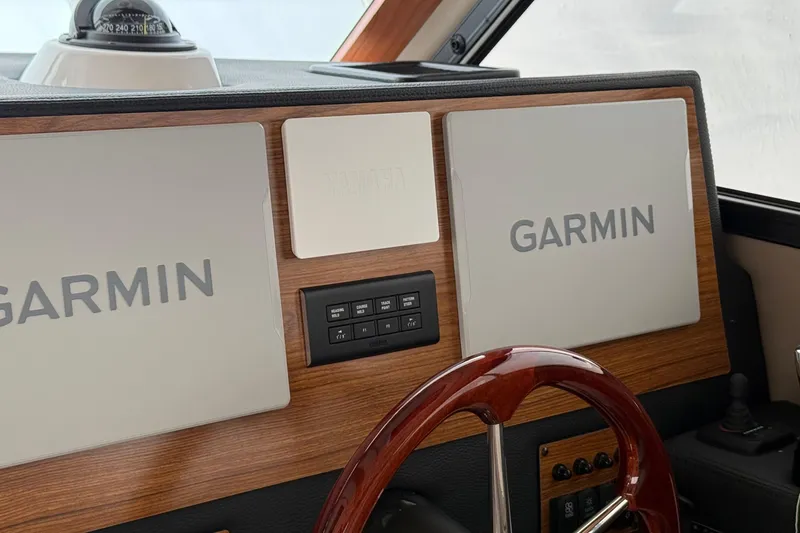 Slide: The Image of 2025 Cutwater C-32 CB dashboard featuring Garmin navigation displays and a wooden steering wheel. - 18