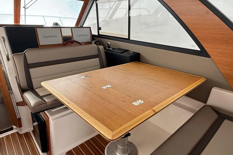 Slide: The Image of 2025 Cutwater C-32 CB interior with wooden table, cushioned seating, and Garmin navigation displays. - 19
