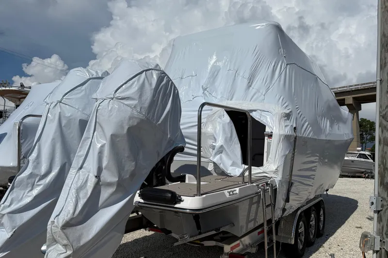 Slide: The Image of 2025 Cutwater C-32 CB boat covered in protective wrap on a trailer, under cloudy sky. - 2