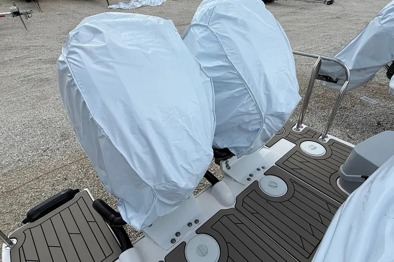 Slide: The Image of Covered outboard motors on a 2025 Cutwater C-32 CB boat, resting on a gravel surface. - 4