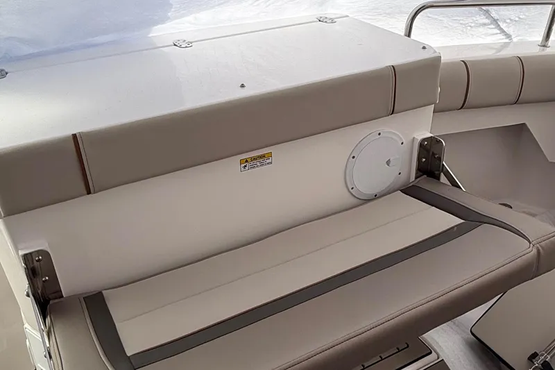 Slide: The Image of 2025 Cutwater C-32 CB boat seating area with beige cushions and safety warning label. - 9