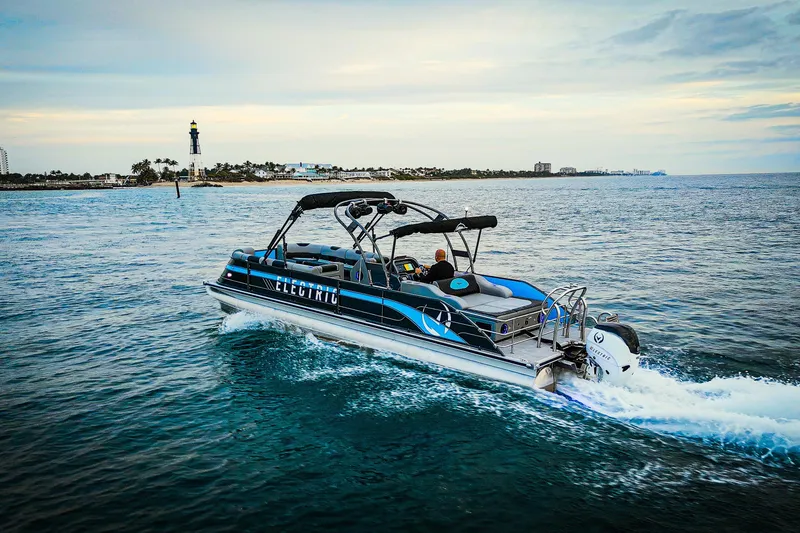 The Image of Electric Vision Marine Technologies V30 boat cruising near a lighthouse, 2025 model. - 0