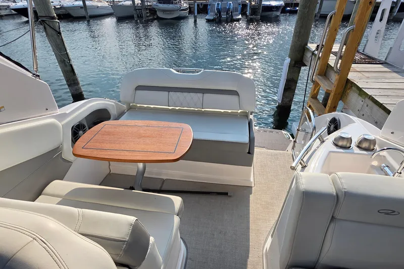 Slide: The Image of 2022 Regal 28 Express boat interior with seating and table, docked at marina. - 14