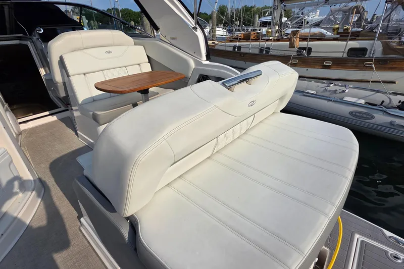Slide: The Image of 2022 Regal 28 Express boat interior with white seating and wooden table, docked at marina. - 16