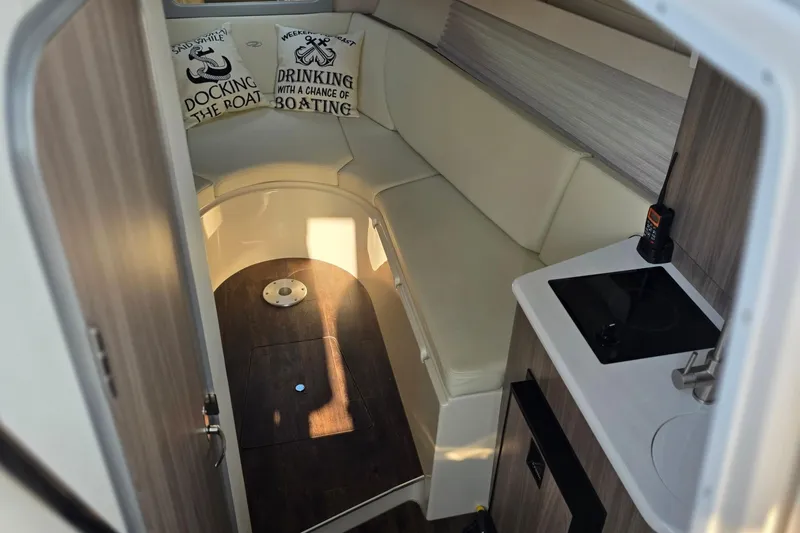 Slide: The Image of 2022 Regal 28 Express cabin interior with seating, pillows, and kitchenette. - 30