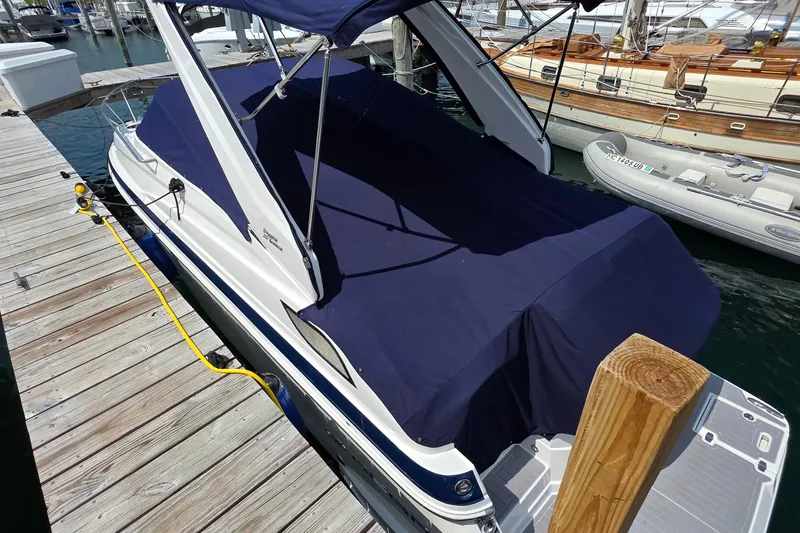 Slide: The Image of 2022 Regal 28 Express boat docked with navy cover, wooden pier, and nearby vessels. - 8