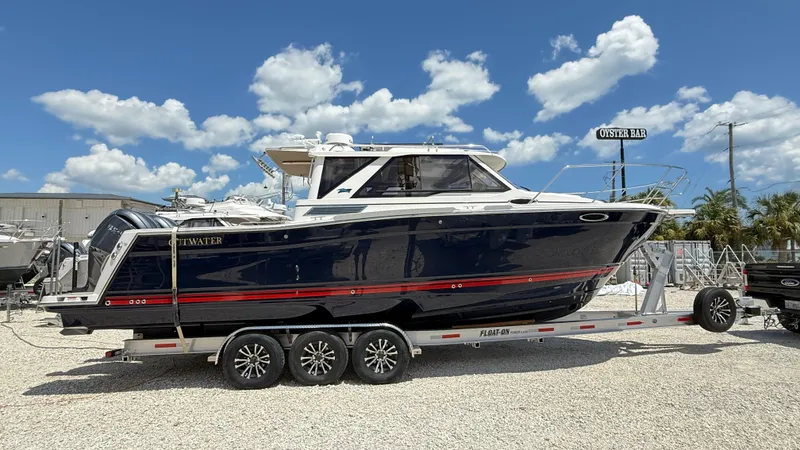 Slide: The Image of 2026 Cutwater C-288 Coupe boat on trailer under blue sky. - 2
