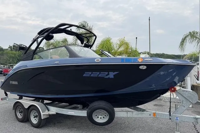 The Image of 2024 Yamaha Boats 222XD on trailer, sleek design, black and blue exterior, parked outdoors. - 0