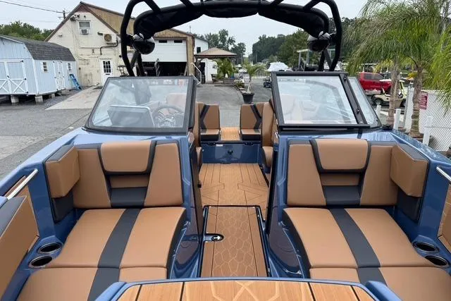 Slide: The Image of 2024 Yamaha Boats 222XD interior with tan and black seating, docked outdoors. - 13