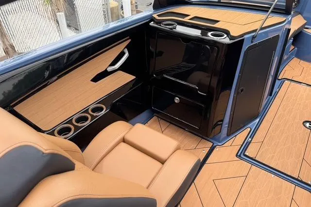 Slide: The Image of 2024 Yamaha Boats 222XD interior with tan seating, black accents, and wood-style flooring. - 18