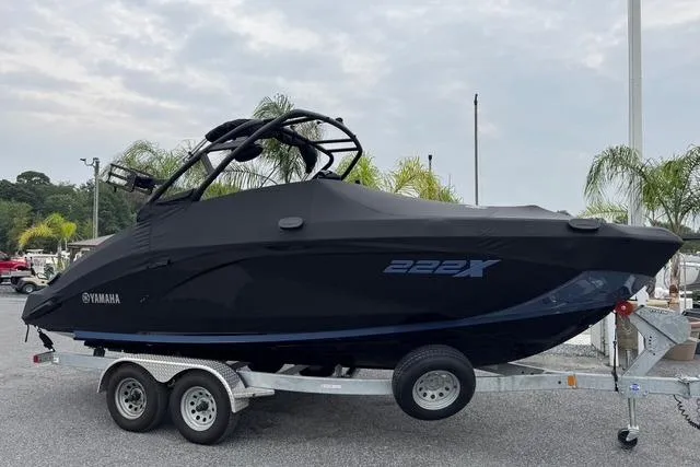 Slide: The Image of 2024 Yamaha Boats 222XD covered on trailer, parked outdoors with palm trees in background. - 3
