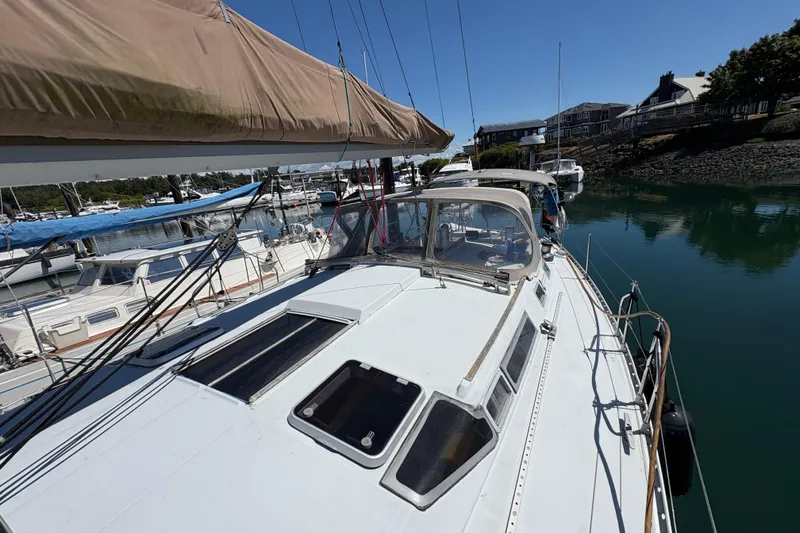 Slide: The Image of 1990 Beneteau Oceanis 500 sailboat docked in a serene marina setting. - 27