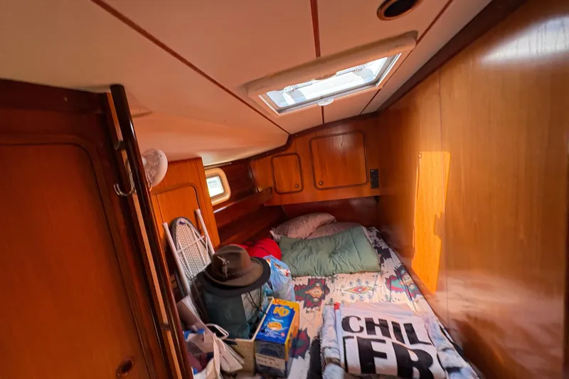 Slide: The Image of Cozy cabin interior of 1990 Beneteau Oceanis 500 sailboat with bedding and personal items. - 99