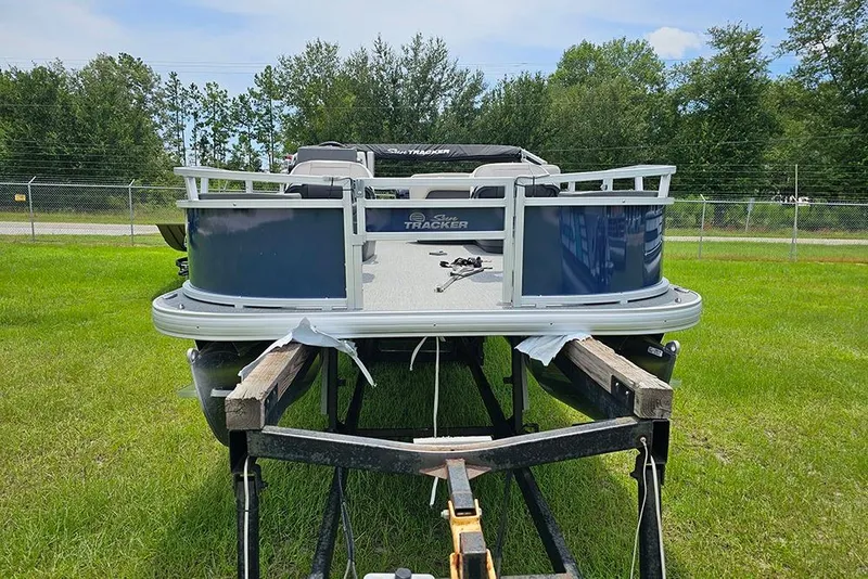 Slide: The Image of 2026 Sun Tracker Bass Buggy 18 DLX pontoon boat on trailer, parked on grass. - 4