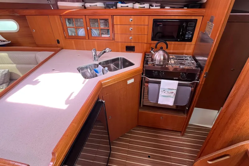 Slide: The Image of Hunter 36-2 yacht kitchen with sink, stove, and microwave, featuring wooden cabinetry, 2006 model. - 17