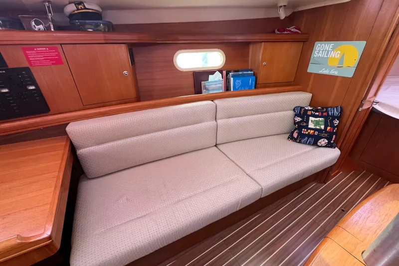 Slide: The Image of 2006 Hunter 36-2 yacht interior with cushioned seating, nautical decor, and wooden cabinetry. - 25